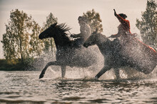 Cossacks In Old Fashion Costumes Ride On Horseback On Water And Field Background. Water Drops