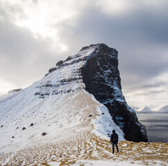 Poster - Beautiful view of a hiker male in front of a high snowy rocky hill against a light blue sky