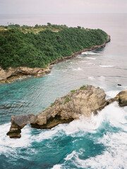 Sticker - Vertical shot of a rocky cliff surrounded by the ocean