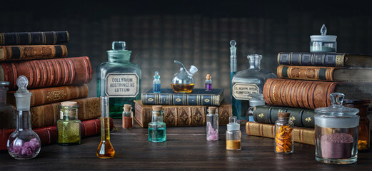 Wall Mural - Glass bottles, old books on table of a scientist. Medicine, chemistry, pharmacy, apothecary, alchemy history background. Translation from labels-eyewash astringent, morphine hydrochloride and almonds.