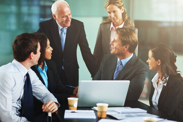 Wall Mural - Theyre impressed with his progress. Cropped shot of a group of businesspeople gathered around a laptop in the office.