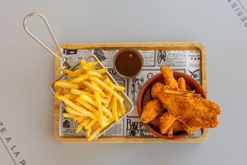 Poster - Closeup of delicious french fries, nuggets with the Spanish flag, and a sauce on a wooden board