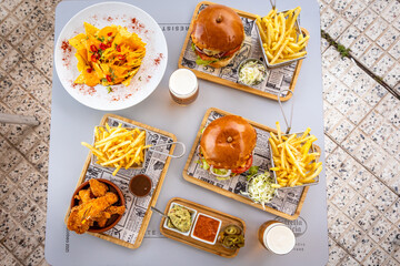 Wall Mural - Closeup of a snack table with delicious burgers and french fries on a wooden board