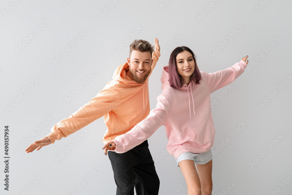 Cool young couple in hoodies on light background