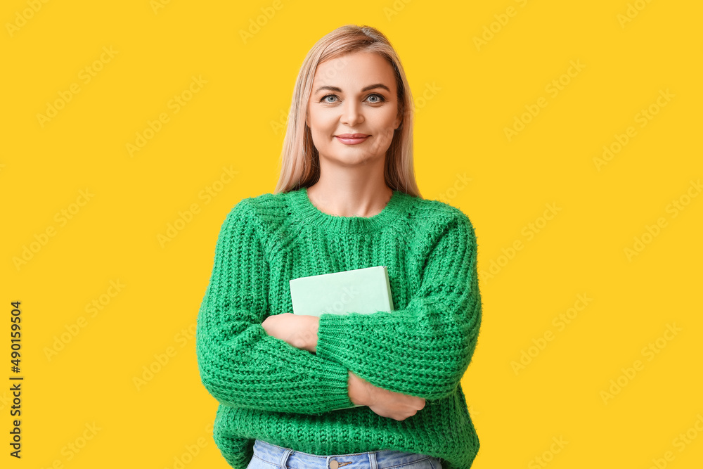 Beautiful woman with book on yellow background