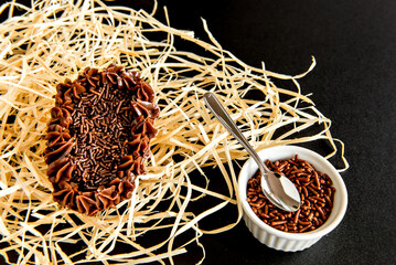 Easter egg filled with brigadeiro on black background, easter egg spoon, top view.