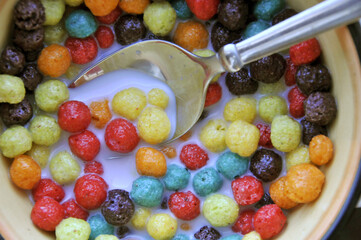 Sticker - Close-up top view of a bowl of colorful fruit-flavored breakfast cereal with milk and spoon to eat