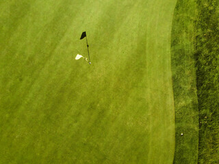 Wall Mural - Aerial top view of a yellow flag with a shadow on the grass in a golf course