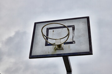 Wall Mural - Rusty basketball hoop without net on a cloudy sky background