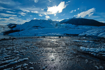 Sticker - Closeup shot of a frozen lake surrounded by snow-covered mountain range