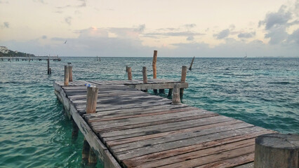 Wall Mural - photo of a wooden walkway over the sea at sunset