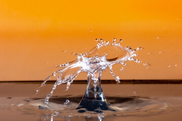 Sticker - Closeup shot of a water splash in a studio on an orange background