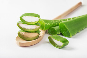 Wall Mural - Leaves of Aloe vera plant in wooden spoon over white background. Natural ingredient for herbal beauty product, cosmetology, dermatology, naturopathic medicine