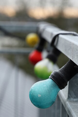 Poster - Vertical shot of frozen colorful light bulbs on metal fence