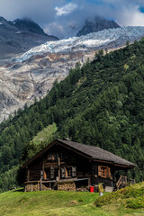 Wall Mural - Vertical beautiful shot of a house on the hill in the background of the mountains.