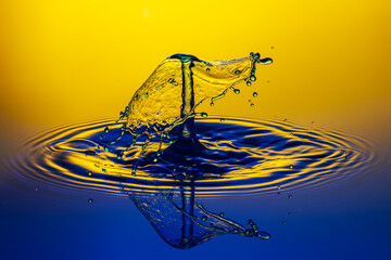 Wall Mural - Close-up shot of a water splash in a blue tone with yellow background