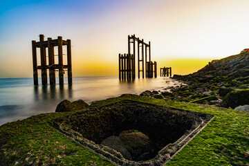 Wall Mural - Scenic view of wooden constructions next to the sea with colorful sky in the background