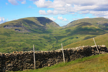 Poster - Old stone fence with green hill and blue sky on the background