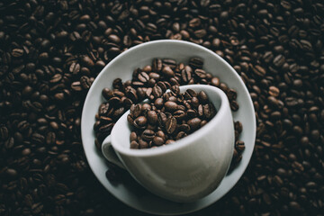 Wall Mural - Closeup shot of roasted coffee beans in white cups and saucer