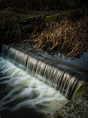 Poster - Vertical shot of a small waterfall with long exposure in the daylight - perfect for wallpapers