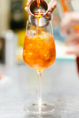 Wall Mural - Vertical closeup of the hand preparing an Aperol Spritz drink.