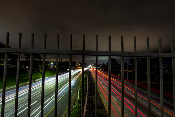 Wall Mural - Closeup shot of a metal fence with an asphalt road in the background