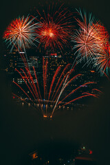 Wall Mural - Vertical shot of fireworks over a cityscape