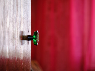 Sticker - Shallow focus of a shiny red wooden door with a doorknob reflectinf a red vurtain