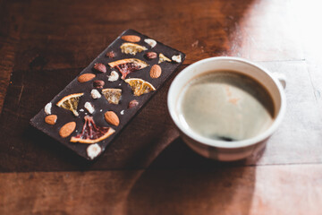 Wall Mural - Cup of coffee and chocolate bar with nuts and dried fruit on a wooden table