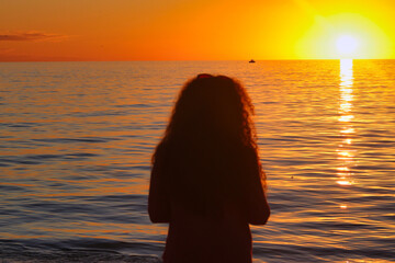 Canvas Print - Silhouette of the woman against the beautiful sunset above the sea.