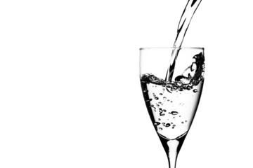 Wall Mural - Closeup of a drinking glass with water being poured against the white background