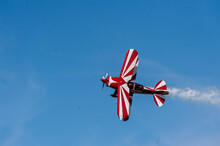 Red And White Biplane Flying Against A Blue Sky