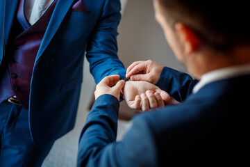 Sticker - Selective focus shot of a best man putting a watch around the groom's wrist on a wedding