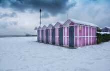 Beautiful Snowy View Of A Beach And Beach Huts Under The Snow Against A Gray Cloudy Sky