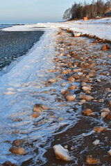 Sticker - Vertical shot of frozen snowy stones on a seashore