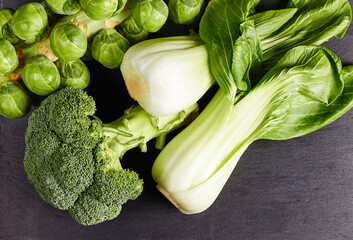 Wall Mural - Top view of ripe broccoli, brussels sprout and bok choy on a dark wooden table