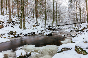 Poster - View of Harz mountain river Ilse in Ilsenburg with ice and snow at wintertime Germany with the bride