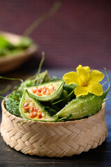 Wall Mural - Small bitter gourd or bitter melon in bamboo basket on wooden background, Food ingredients and herbal medicine