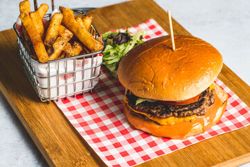 Canvas Print - Closeup shot of an appetizing burger with French fries on a wooden board