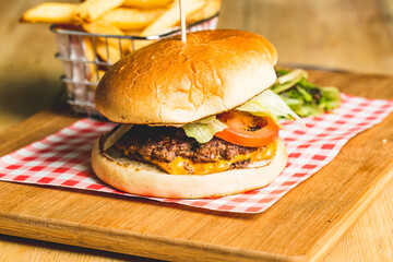 Canvas Print - Closeup shot of an appetizing burger with French fries on a wooden board