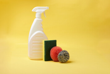 Poster - Bottle of cleaning fluid and different sponges isolated on a yellow background