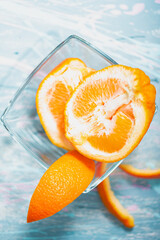 Poster - Top view of peeled tangerine fruit and its peels in a transparent glass bowl on a blue and whit