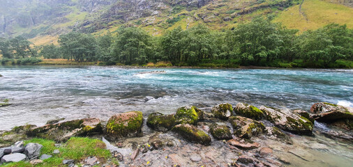 Canvas Print - Beautiful shot of a flowing river surrounded by greenery-covered hills