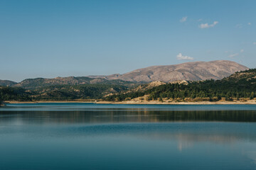 Sticker - Beautiful shot of Apolaki lake surrounded by greenery-covered hills in Rhodes, Greece