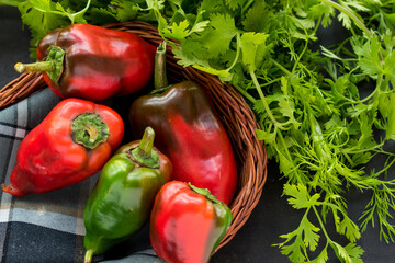 Wall Mural - Closeup shot of an assortment of fresh red and green peppers, coriander in a basket