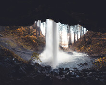 View Of An Amazing Waterfall From The Cave Facing An Autumn Forest