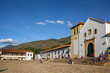 View to the Church of our Lady of the Rosary and historical buildings at Plaza Mayor of Villa de Leyva, against blue sky, mountains in background, Colombia
