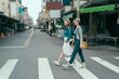 © PR Image Factory - side view full length of young female people walking around in town. two smiling girl travelers cross zebra road in taipei taiwan. women traveler relax sightseeing in local traditional market outdoor