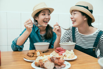 Wall Mural - Group of young female friends wearing straw hats enjoying taiwanese local meal in street food vendor. cheerful ladies smiling holding spoon eating tasty dishes indoors together. happy women tourists