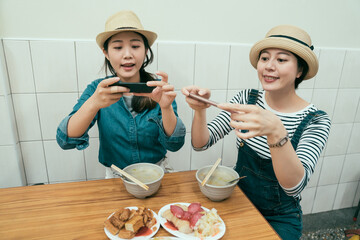 Wall Mural - Group of female friend take picture with mobile phone before have lunch in taipei taiwan. young attractive girls smiling holding cellphone photographing local street food in vendor store restaurant.